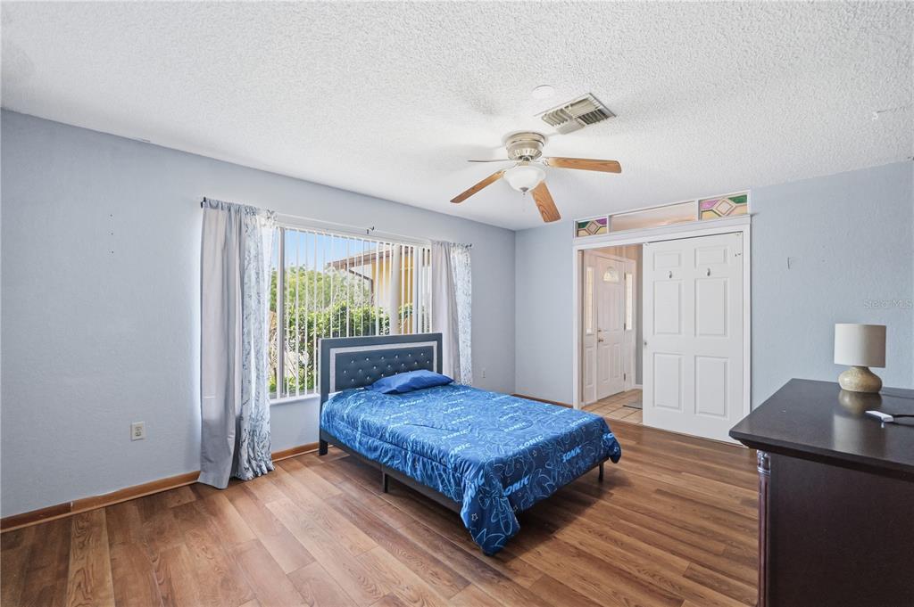 A bedroom with light blue walls, wood-look flooring, a ceiling fan, and a single bed — 9470 MONTEBELLO LANE, SPRING HILL, FL