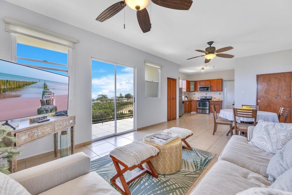 An open-concept living area features tile flooring, a kitchen, and a sliding door to a balcony — 413 CAM. CARRETAS UNIT A7, RINCON, PR
