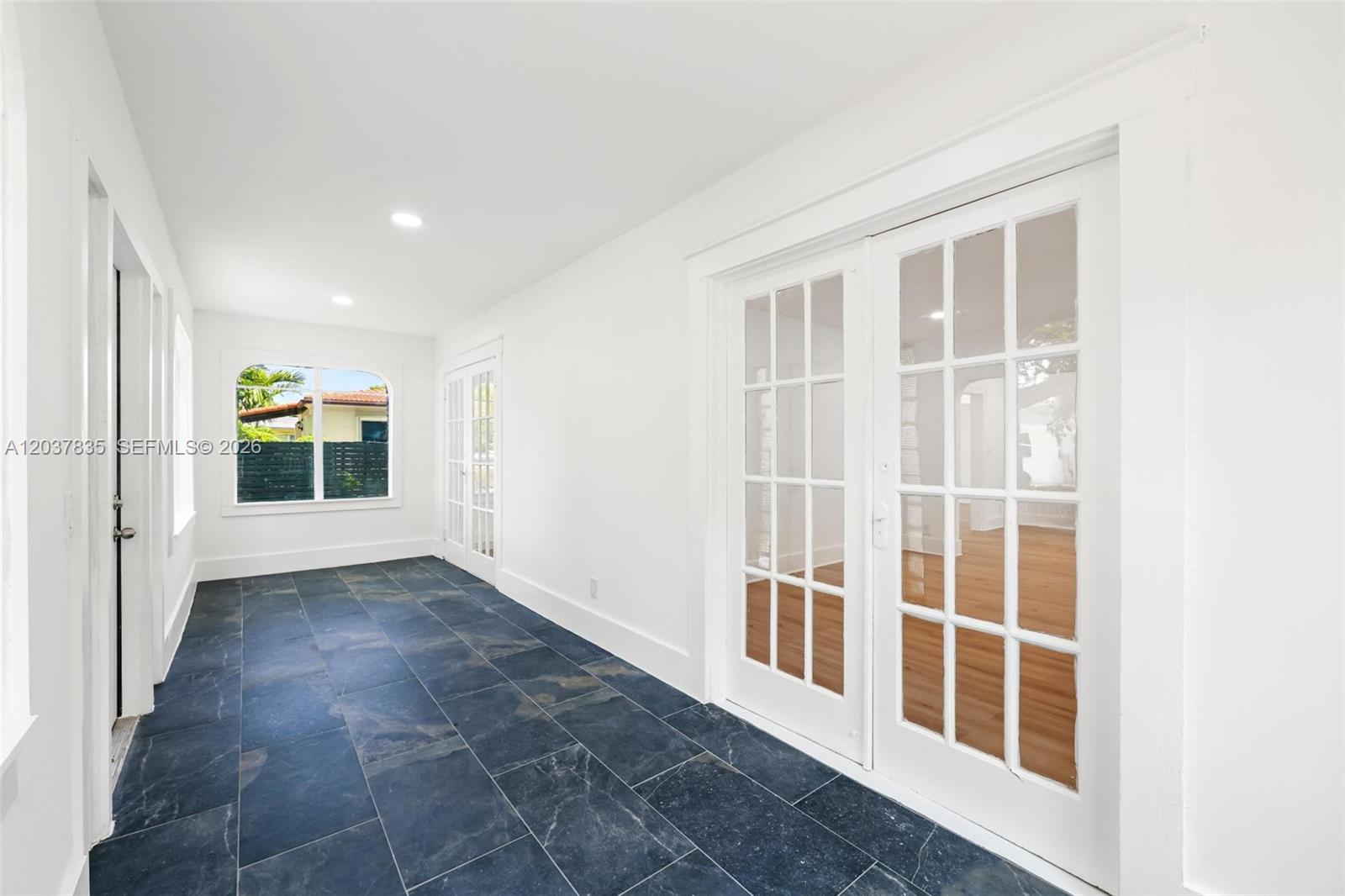 A sunroom features dark slate tile flooring, white walls, and multiple sets of French doors — 1954 Dewey St, Hollywood FL 33020, HOLLYWOOD, FL