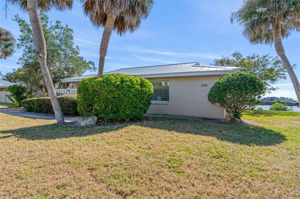 The exterior of a single-story house features a metal roof, beige siding, and palm trees — 11568 W BAYSHORE DRIVE UNIT 17, CRYSTAL RIVER, FL
