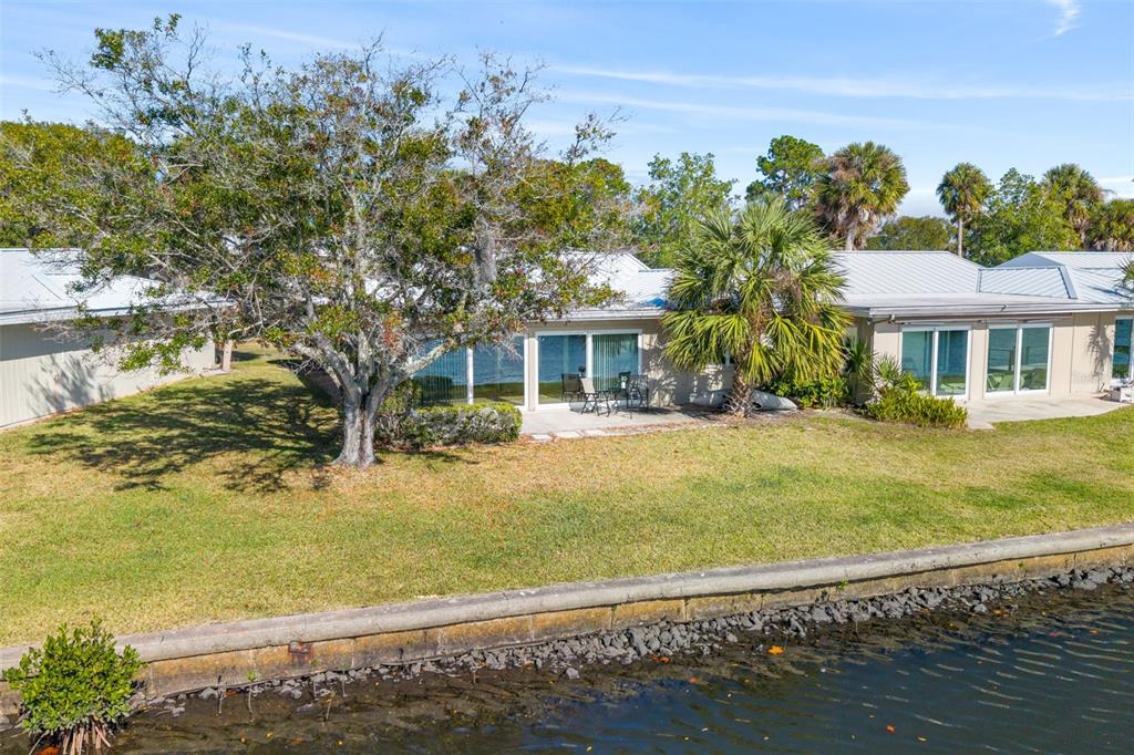 A waterfront residential building with a large tree, a patio, and a concrete seawall — 11568 W BAYSHORE DRIVE UNIT 17, CRYSTAL RIVER, FL
