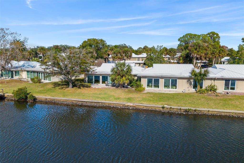 An exterior view of a waterfront residential building with a lawn and palm trees — 11568 W BAYSHORE DRIVE UNIT 17, CRYSTAL RIVER, FL