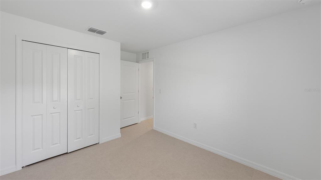 A bedroom with white walls, beige carpet, a white closet, and an open doorway — 377 ATWATER STREET, PORT CHARLOTTE, FL