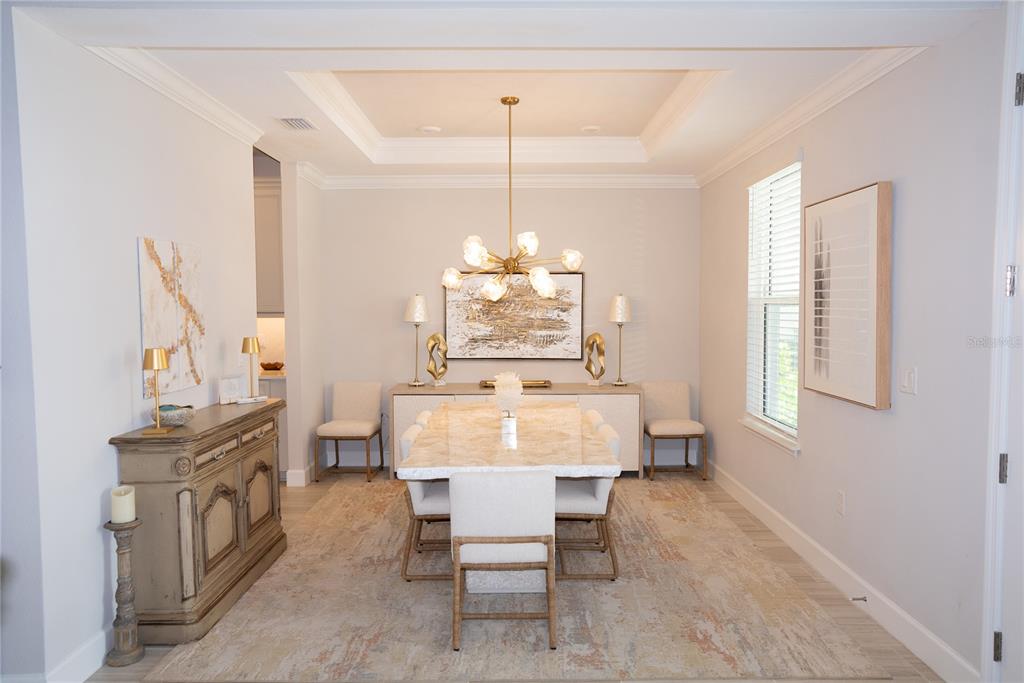 A dining room features a marble table, a gold chandelier, and a neutral area rug — 9217 TORRENT TRAIL, SARASOTA, FL