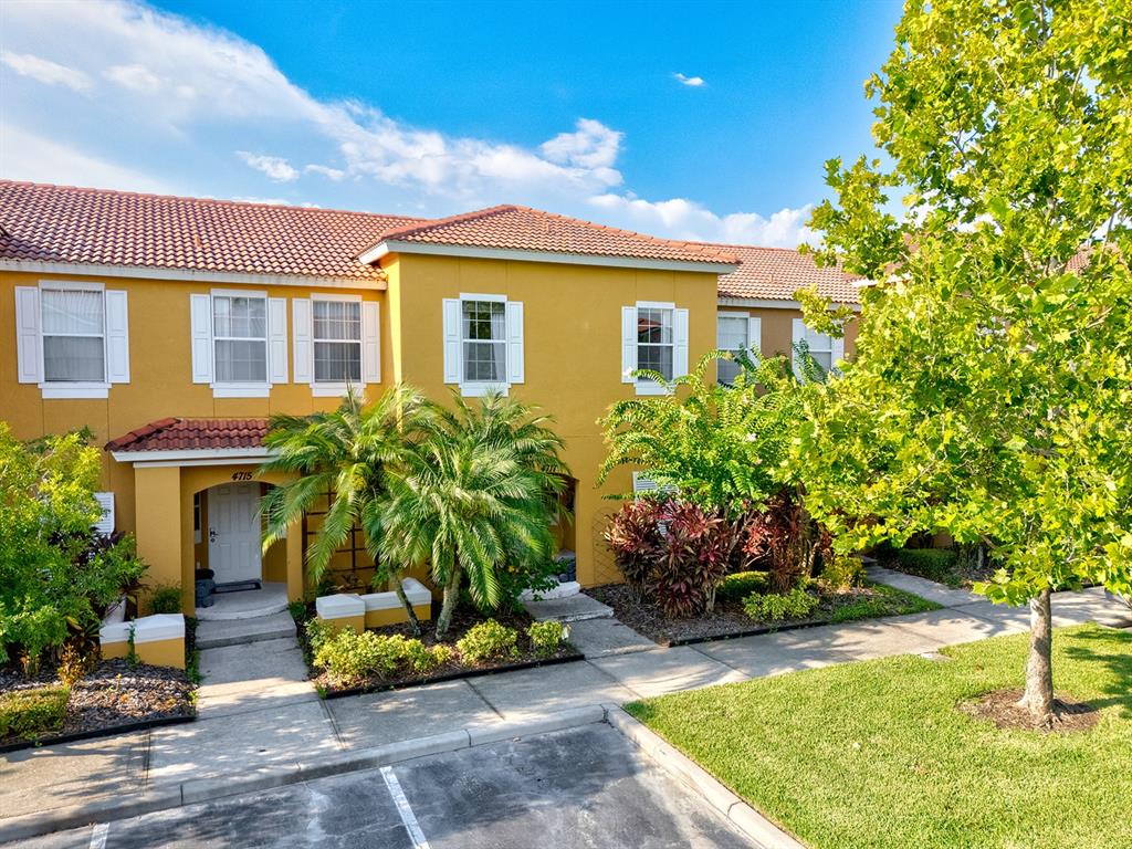 An exterior view of a two-story yellow townhouse with a tiled roof and palm trees — 4717 FLAGLER BEACH WAY, KISSIMMEE, FL