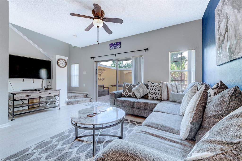A living room features a gray sectional sofa, a marble coffee table, and a television — 4717 FLAGLER BEACH WAY, KISSIMMEE, FL