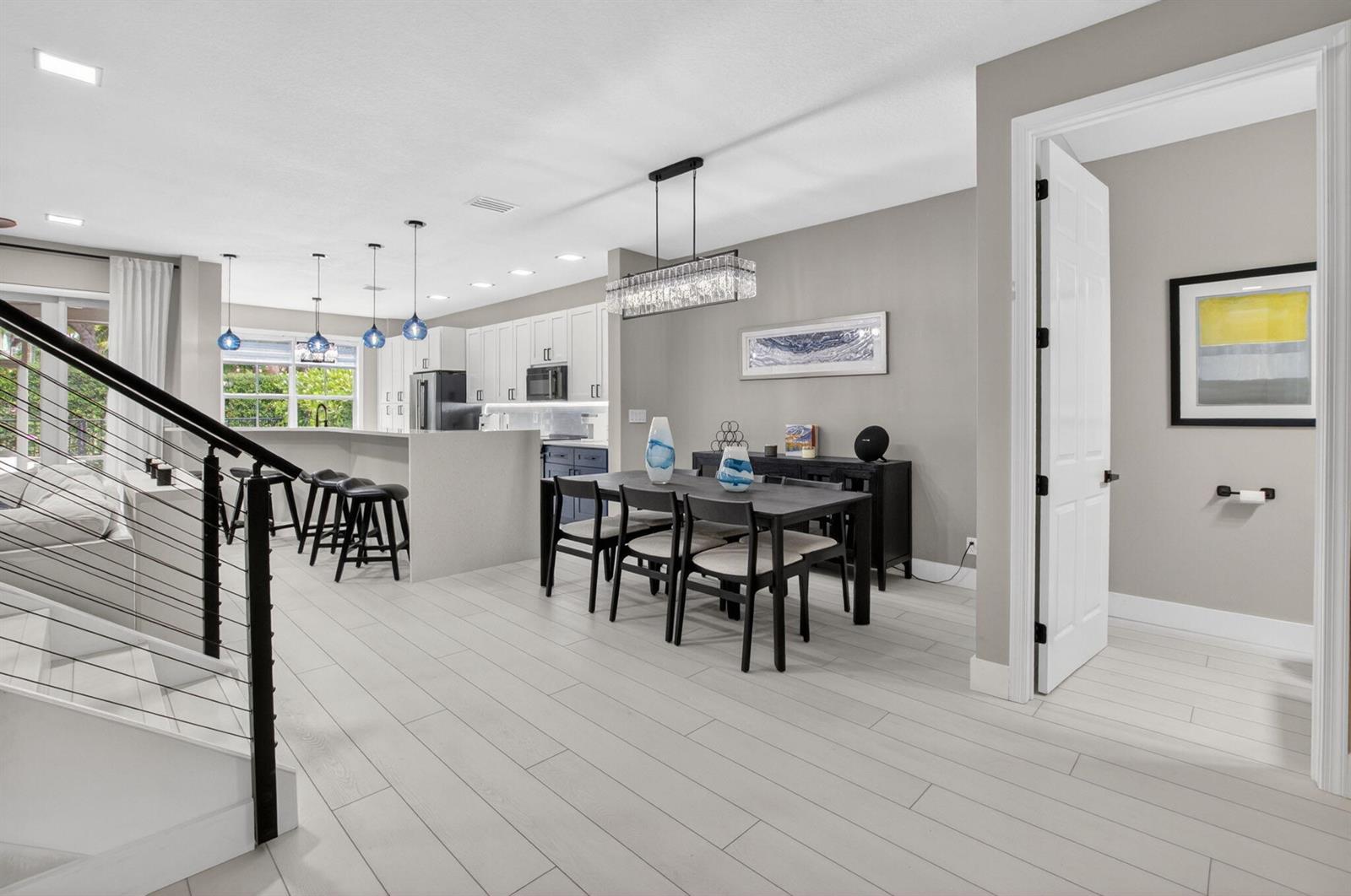 An open-concept dining area and kitchen feature light wood-look flooring and modern light fixtures — 124 Las Brisas Circle, Hypoluxo FL 33462, HYPOLUXO, FL