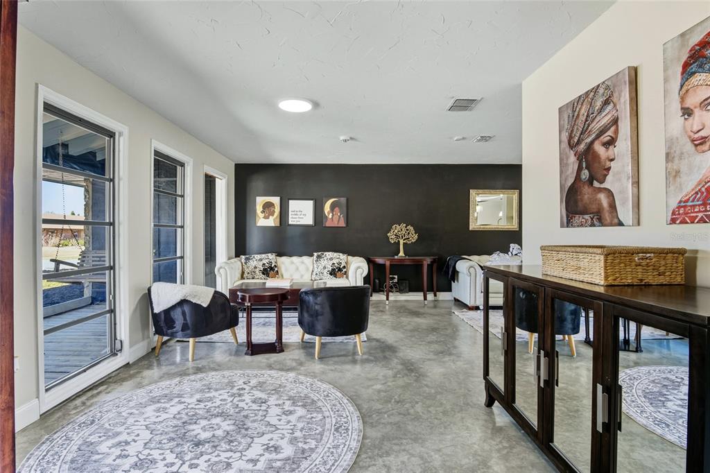 A living room with concrete floors, a black accent wall, and two white tufted sofas — 213 DOVERWOOD ROAD, FERN PARK, FL