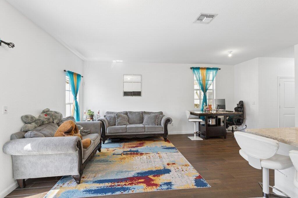 A living room with gray sofas, a colorful area rug, and a desk near a window — 4008 NW 11th Drive, Lauderhill FL 33313, LAUDERHILL, FL