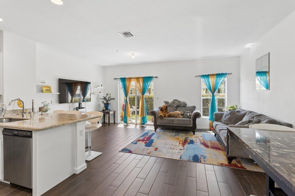 A living room with dark wood-look tile floors, a gray sofa, and colorful curtains — 4008 NW 11th Drive, Lauderhill FL 33313, LAUDERHILL, FL
