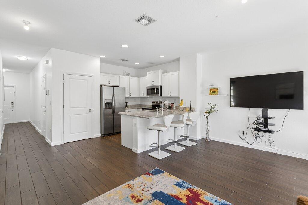 A kitchen with white cabinets and a breakfast bar opens into a living area — 4008 NW 11th Drive, Lauderhill FL 33313, LAUDERHILL, FL