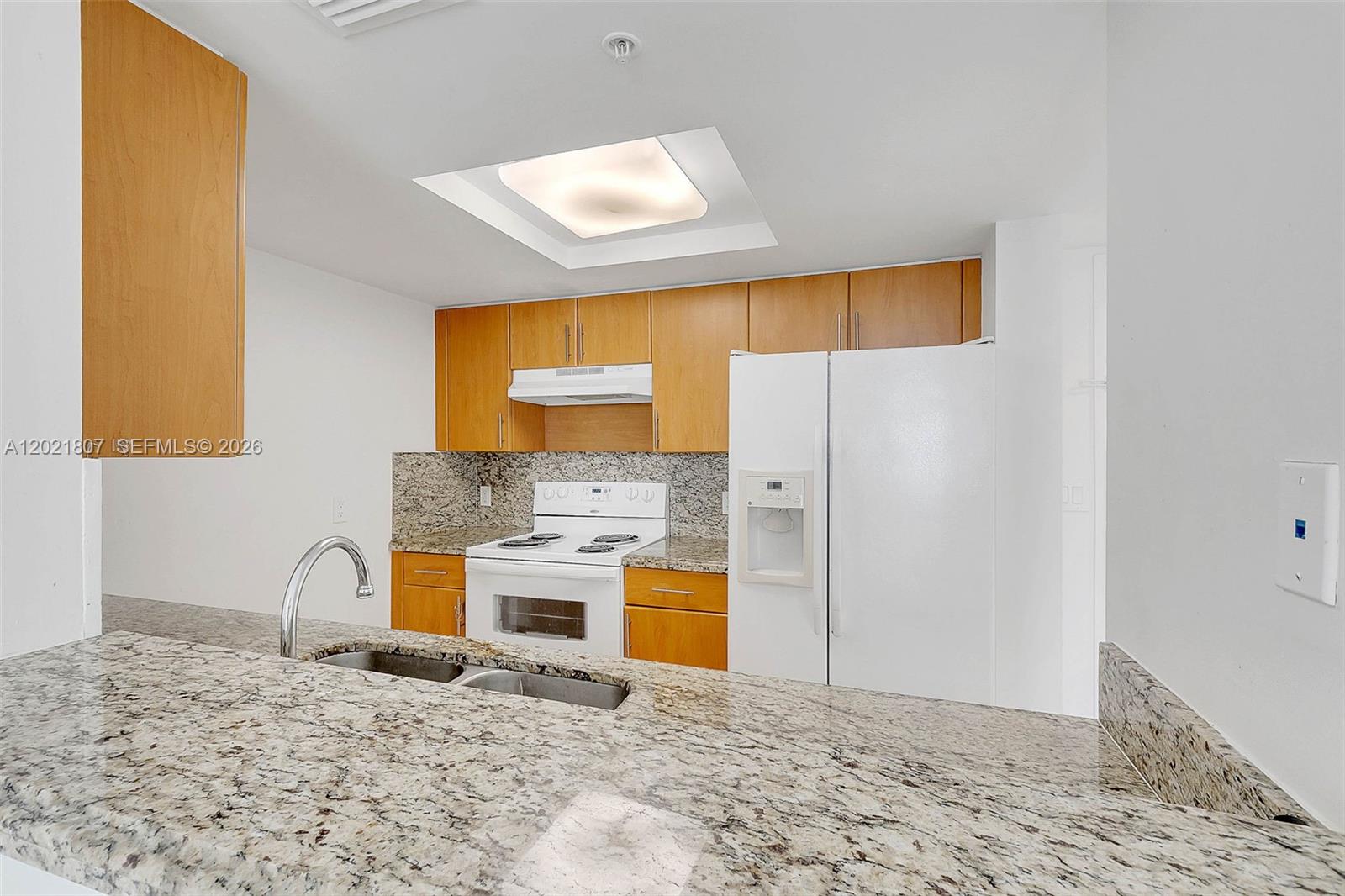 A kitchen features light wood cabinets, granite countertops, and white appliances — 1690 SW 27th Ave # 805, Miami FL 33145, MIAMI, FL