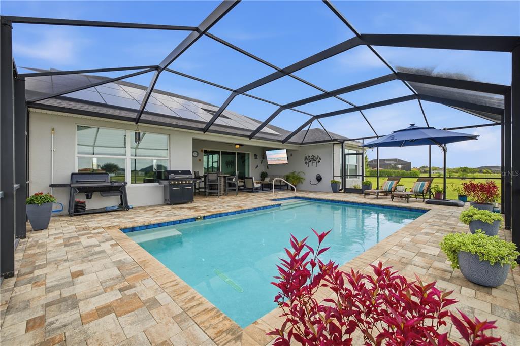 A screened-in patio features a swimming pool, outdoor grill, and lounge seating on a paver deck — 5315 SAN REMO CIRCLE, WIMAUMA, FL