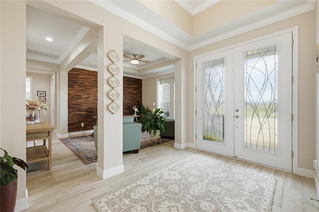 A bright entryway features light wood-look tile floors, a white double door, and an adjacent room — 5315 SAN REMO CIRCLE, WIMAUMA, FL