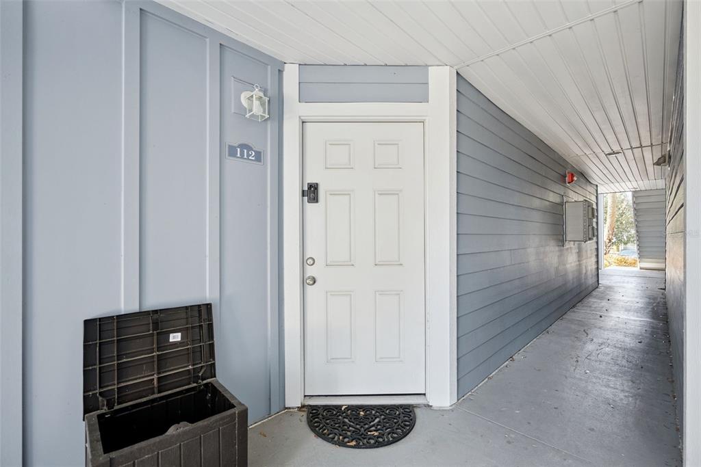 A white front door with a black electronic lock sits on a covered outdoor walkway — 2592 GRASSY POINT DRIVE UNIT 112, LAKE MARY, FL