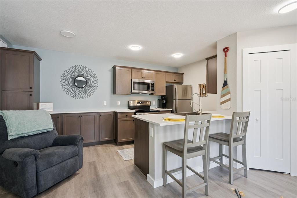 A kitchen features dark wood cabinets, stainless steel appliances, a white island, and two chairs — 2592 GRASSY POINT DRIVE UNIT 112, LAKE MARY, FL