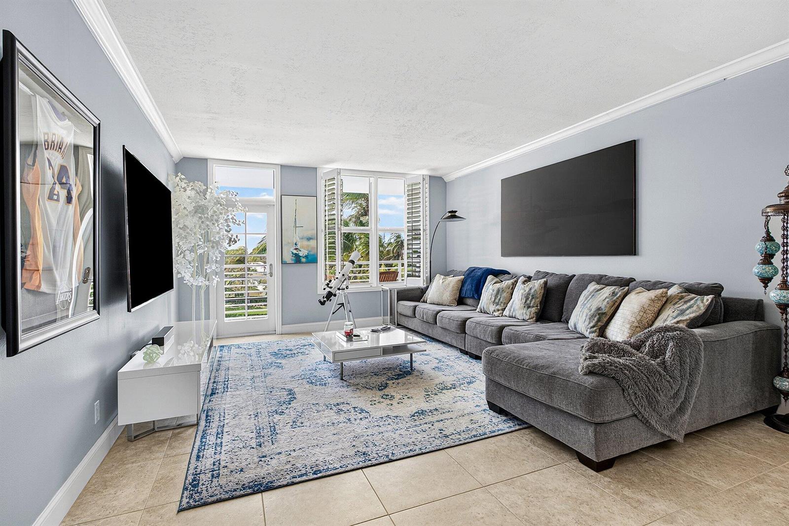 A living room features a grey sectional sofa, a patterned rug, and a balcony door — 2851 S Ocean Boulevard # m, Boca Raton FL 33432, BOCA RATON, FL