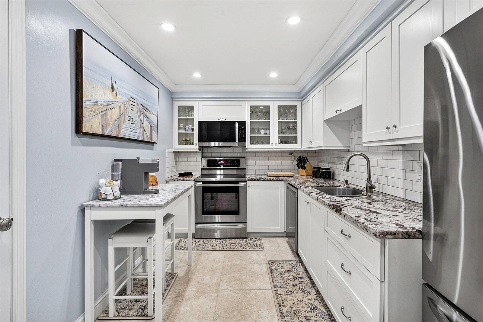 A kitchen features white cabinets, granite countertops, stainless steel appliances, and a small breakfast table — 2851 S Ocean Boulevard # m, Boca Raton FL 33432, BOCA RATON, FL