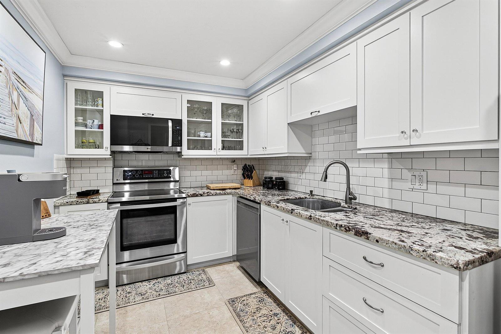 A kitchen features white cabinets, granite countertops, stainless steel appliances, and a subway tile backsplash — 2851 S Ocean Boulevard # m, Boca Raton FL 33432, BOCA RATON, FL
