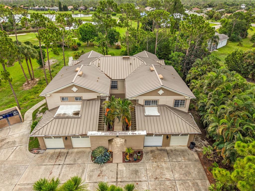 An aerial view of a two-story house with a metal roof and four garage doors — 2090 BIG PASS LANE UNIT D, PUNTA GORDA, FL
