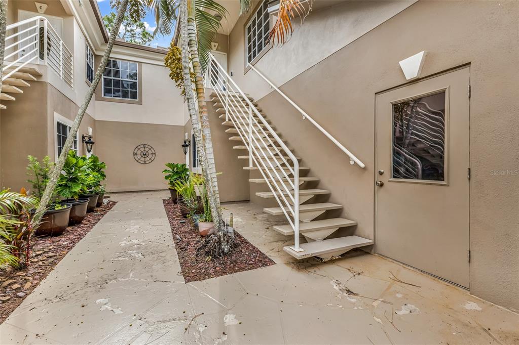 An outdoor staircase leads to an upper level between two beige building walls — 2090 BIG PASS LANE UNIT D, PUNTA GORDA, FL