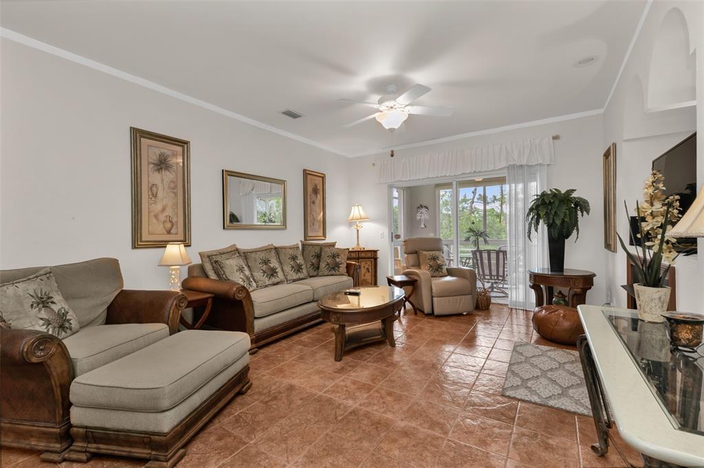 A living room features tile flooring, a ceiling fan, a sofa, and sliding glass doors — 2090 BIG PASS LANE UNIT D, PUNTA GORDA, FL
