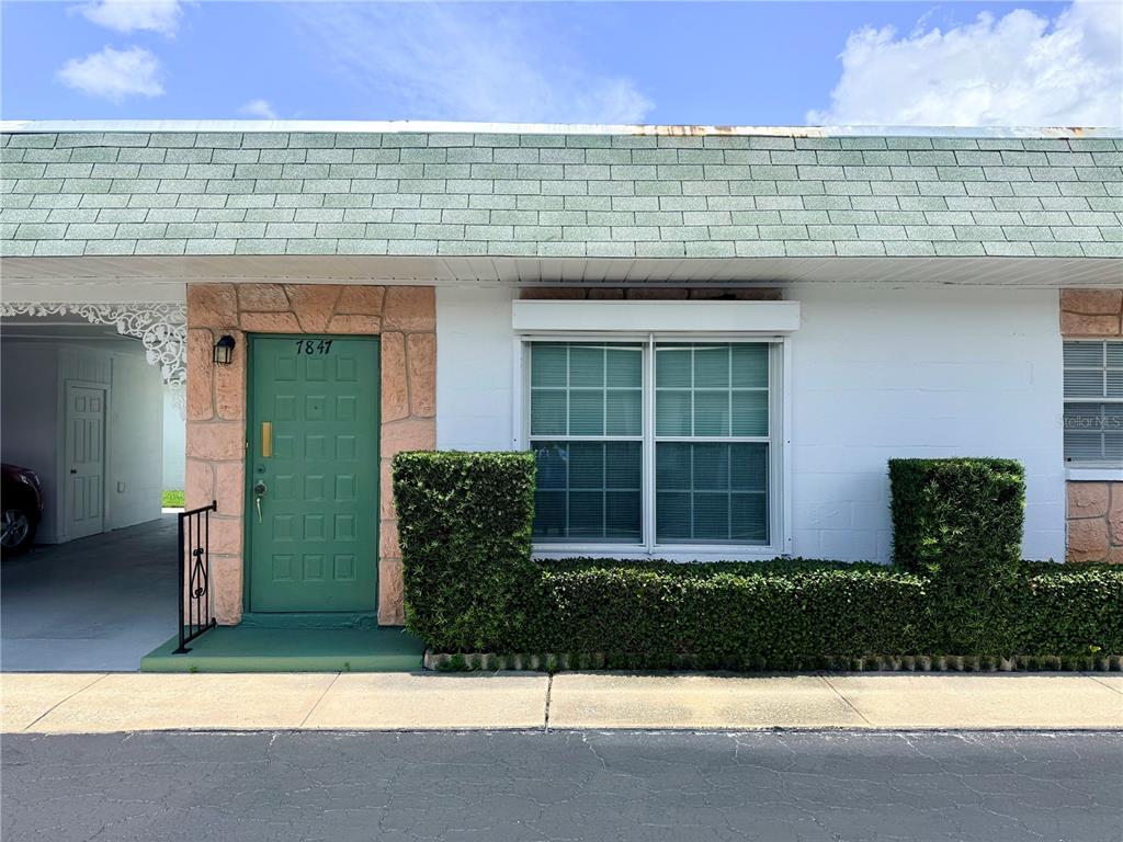 A single-story residence features a green front door, a large window, and a shingled roof — 7847 39TH TERRACE N, ST PETERSBURG, FL