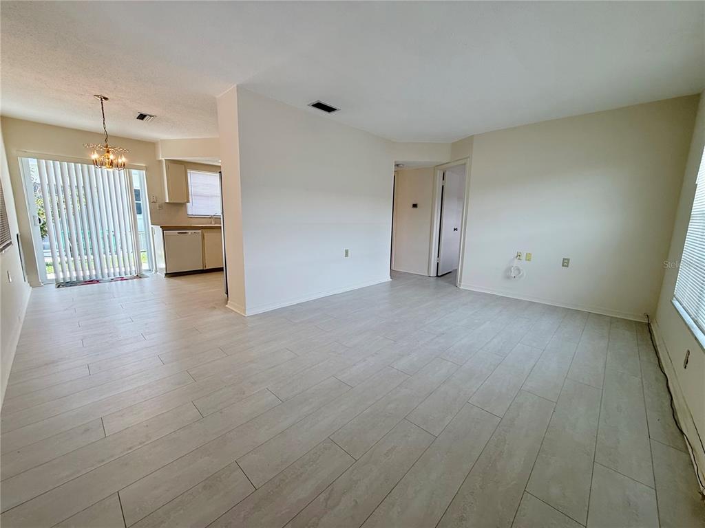 An open-concept living and dining area features light wood-look tile flooring and a sliding door — 7847 39TH TERRACE N, ST PETERSBURG, FL
