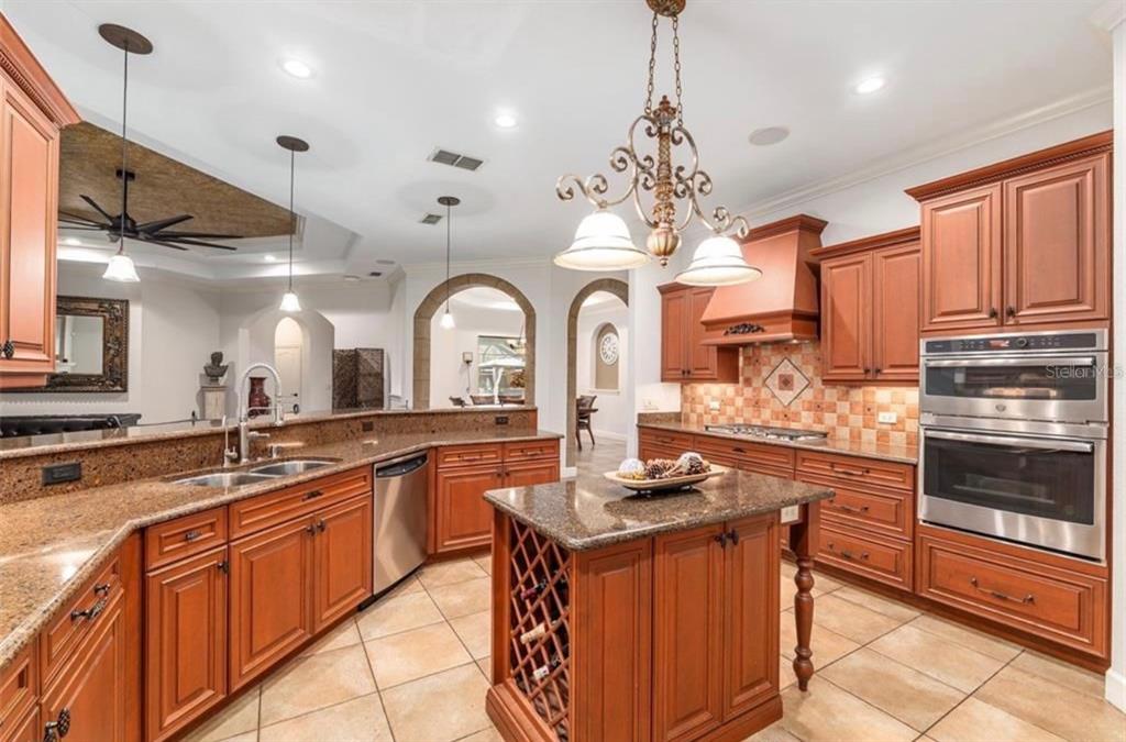 A kitchen with wood cabinets, granite countertops, a center island, and stainless steel appliances — 2901 SE 28TH LANE, OCALA, FL