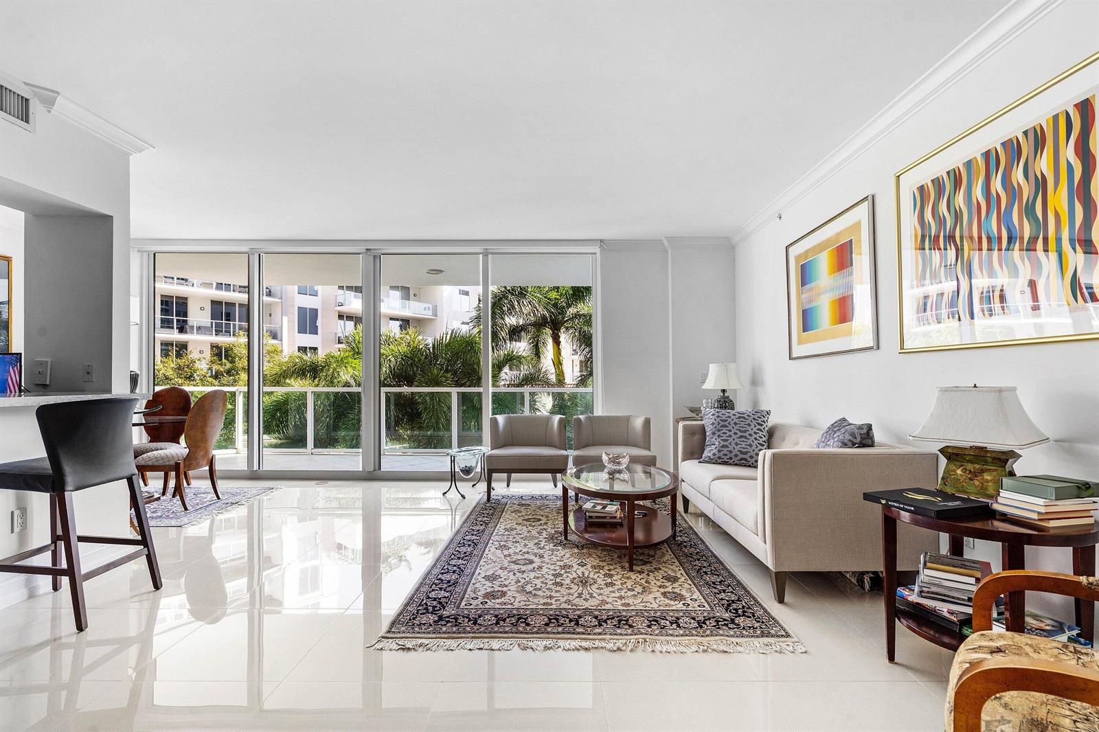 A bright living room features white tile floors, a sofa, armchairs, and floor-to-ceiling windows — 500 SE Mizner Boulevard # A310, Boca Raton FL 33432, BOCA RATON, FL