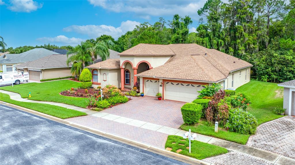 An aerial view shows a single-story house with a tan exterior, brown roof, and driveway — 11421 STRATHAVEN COURT, TRINITY, FL