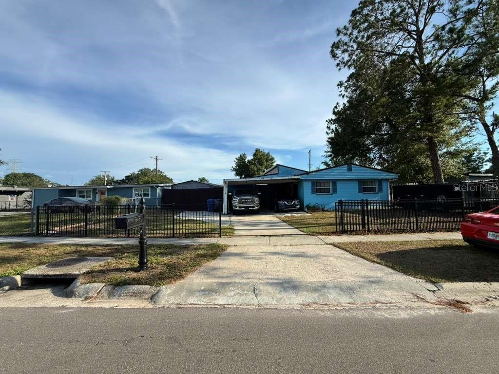 A blue single-story house with a carport and a black metal fence in the front — 7917 RIDEOUT ROAD, TAMPA, FL