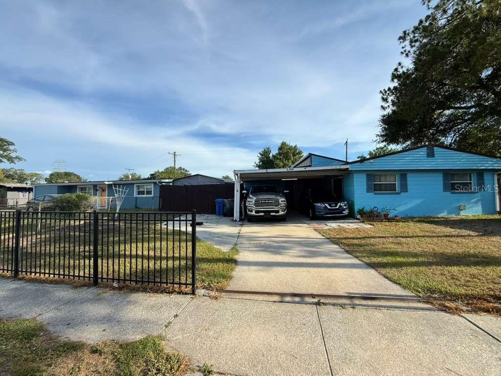 A light blue single-story house features a concrete driveway and a covered carport — 7917 RIDEOUT ROAD, TAMPA, FL