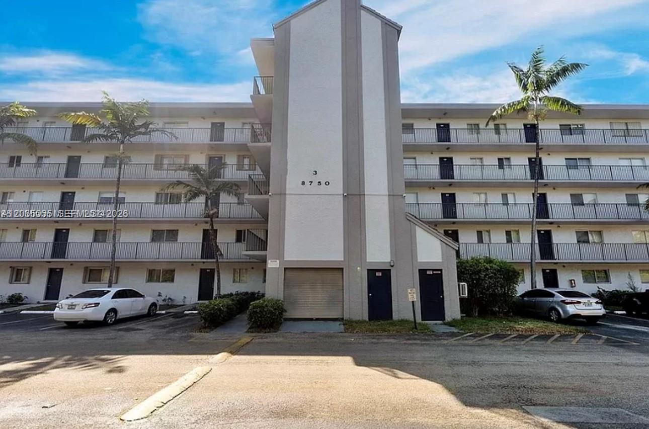 A multi-story apartment building with exterior balconies, a central stairwell, and a parking lot — MIRAMAR, FL