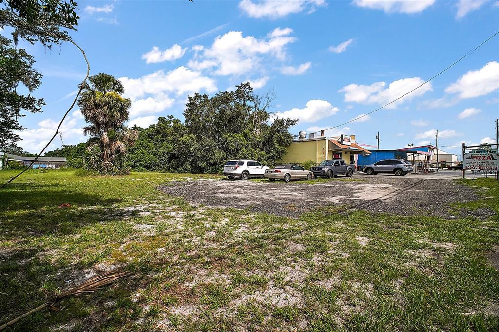 A gravel parking lot sits in front of a small commercial building with a pizza sign — 452 & 438 N PARK AVENUE, APOPKA, FL