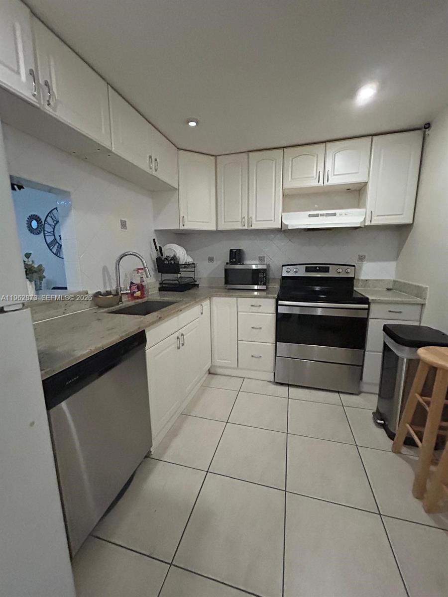 A kitchen features white cabinets, stainless steel appliances, a granite countertop, and tiled flooring — 4314 NW 9th Ave # 3H, Deerfield Beach FL 33064, DEERFIELD BEACH, FL
