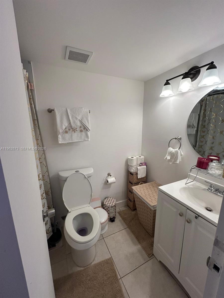 A small bathroom features a white toilet, a vanity with a mirror, and a shower — 4314 NW 9th Ave # 3H, Deerfield Beach FL 33064, DEERFIELD BEACH, FL