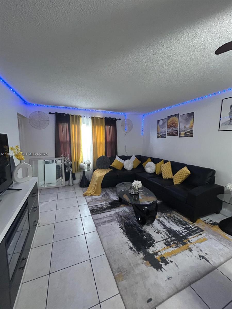 A living room features a black sectional sofa, a patterned area rug, and blue LED lighting — 4314 NW 9th Ave # 3H, Deerfield Beach FL 33064, DEERFIELD BEACH, FL
