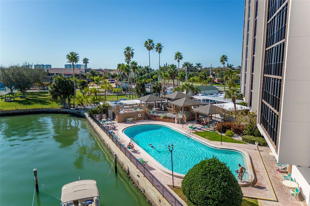 An elevated view of a swimming pool next to a canal with a boat — 10355 PARADISE BOULEVARD UNIT 213, TREASURE ISLAND, FL
