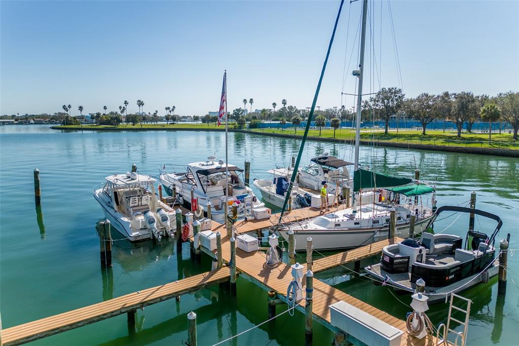 A high-angle view shows several boats docked at a wooden pier on a sunny day — 10355 PARADISE BOULEVARD UNIT 213, TREASURE ISLAND, FL