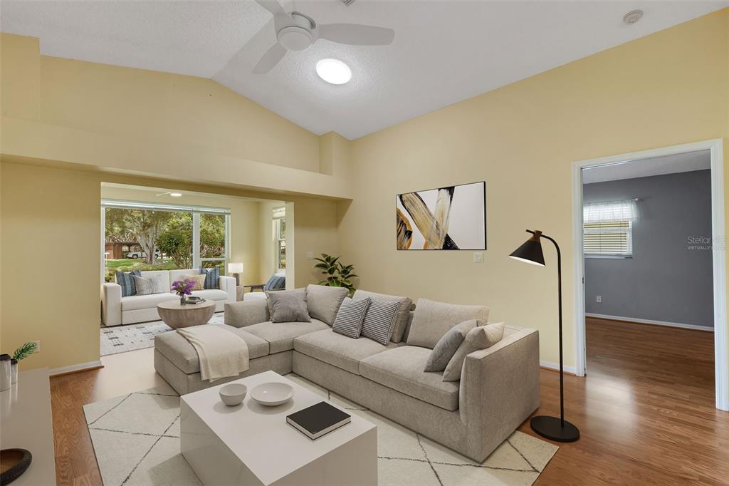 This is a virtually staged living room with a sectional sofa, coffee table, and vaulted ceiling — 4430 FERN DRIVE, BRADENTON, FL