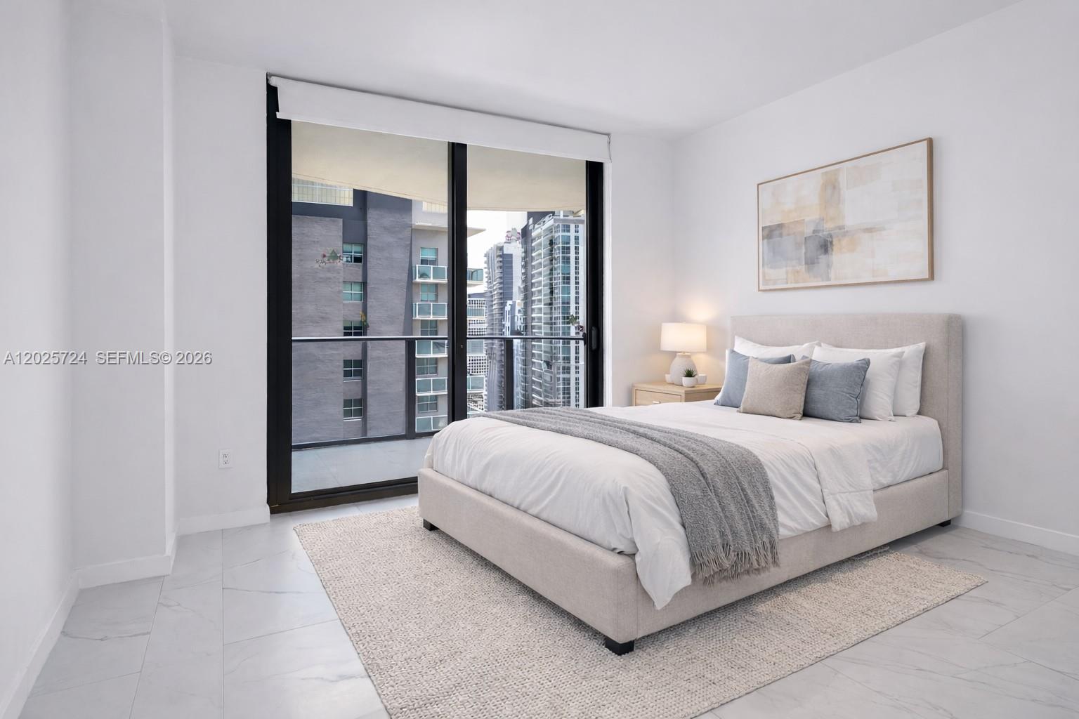 A modern bedroom features a bed, a rug, and a balcony overlooking city buildings — 1300 S Miami Ave # 3211, Miami FL 33130, MIAMI, FL