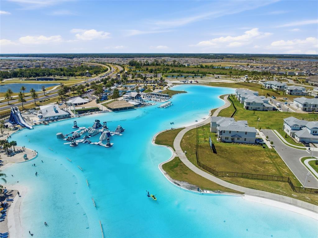 An aerial view shows a large turquoise swimming lagoon with an inflatable water park — 31555 BLUE PASSING LOOP, WESLEY CHAPEL, FL