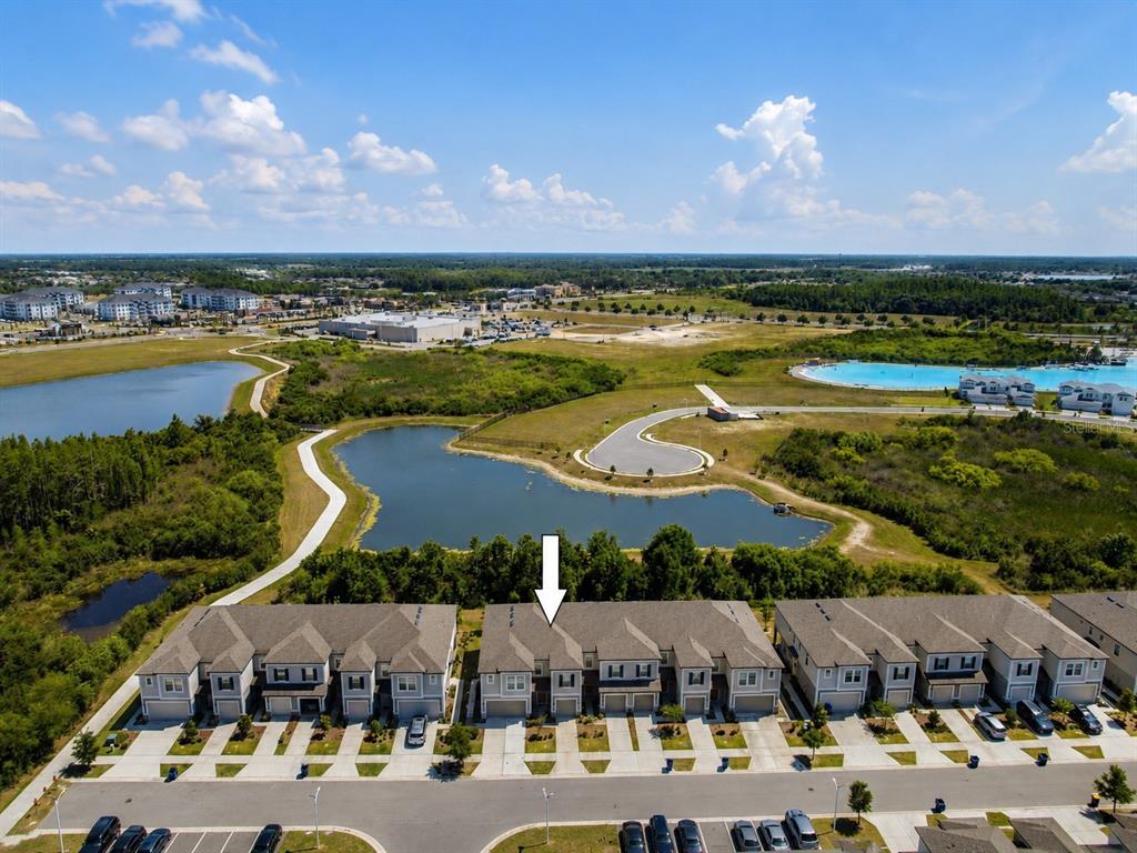 An aerial view shows a row of townhomes overlooking a pond and a large lagoon — 31555 BLUE PASSING LOOP, WESLEY CHAPEL, FL