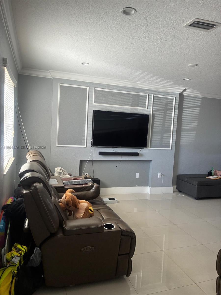 A living room features a wall-mounted television, a brown leather recliner, and light-colored tile flooring — 9425 NW 114th Ln # 3, Hialeah Gardens FL 33018, HIALEAH GARDENS, FL