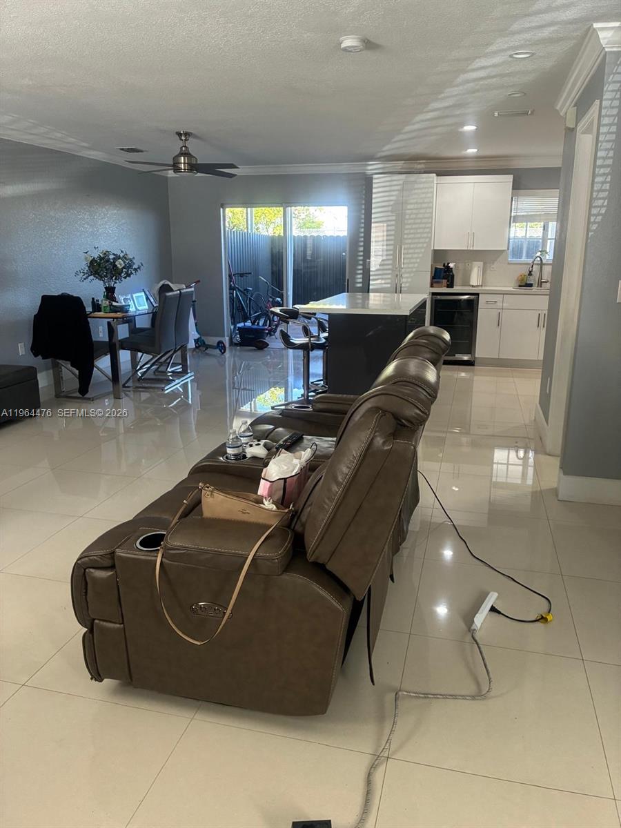A living room with a brown leather sofa, tile floors, and an open kitchen area — 9425 NW 114th Ln # 3, Hialeah Gardens FL 33018, HIALEAH GARDENS, FL