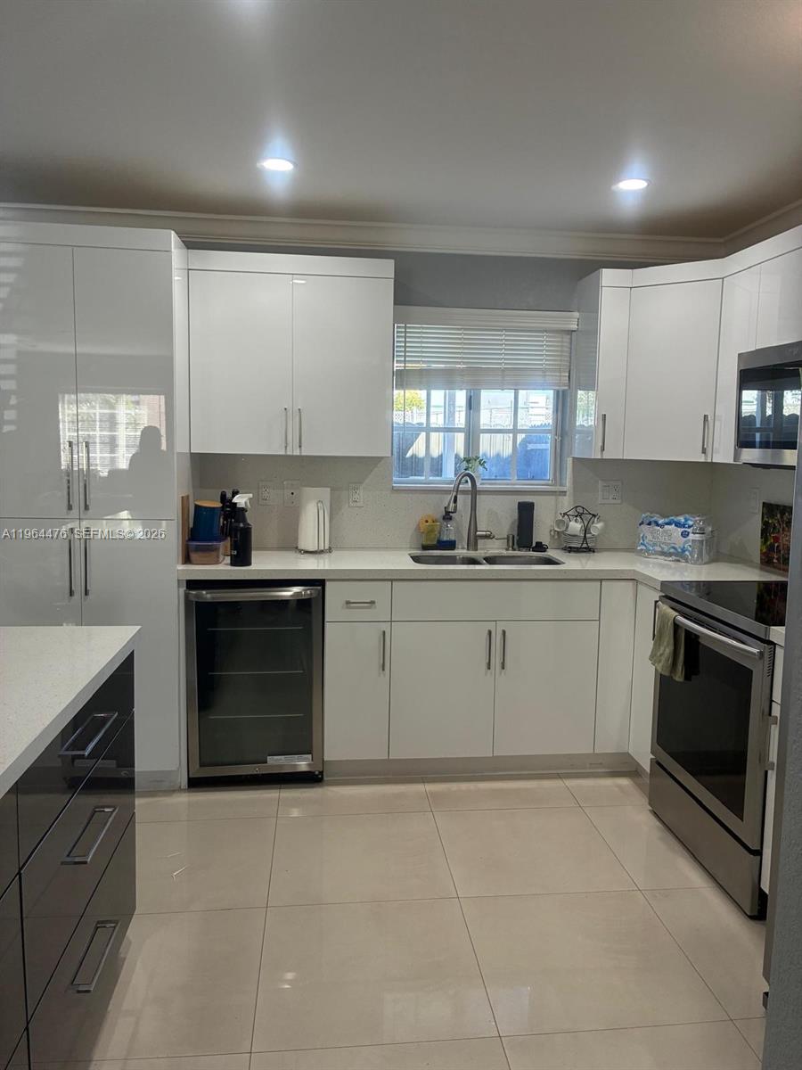 A modern kitchen features white cabinets, stainless steel appliances, and light-colored tile flooring — 9425 NW 114th Ln # 3, Hialeah Gardens FL 33018, HIALEAH GARDENS, FL