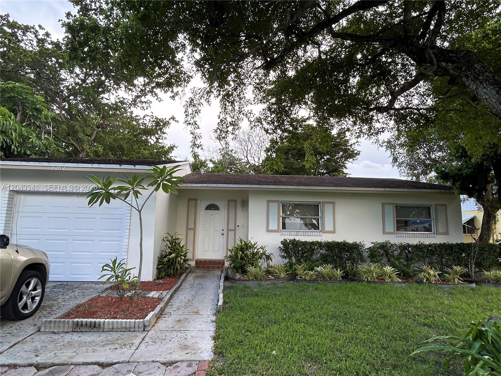 A single-story house features a white exterior, a front garage, and a landscaped front yard — 7262 SW 1st St, Margate FL 33068, MARGATE, FL