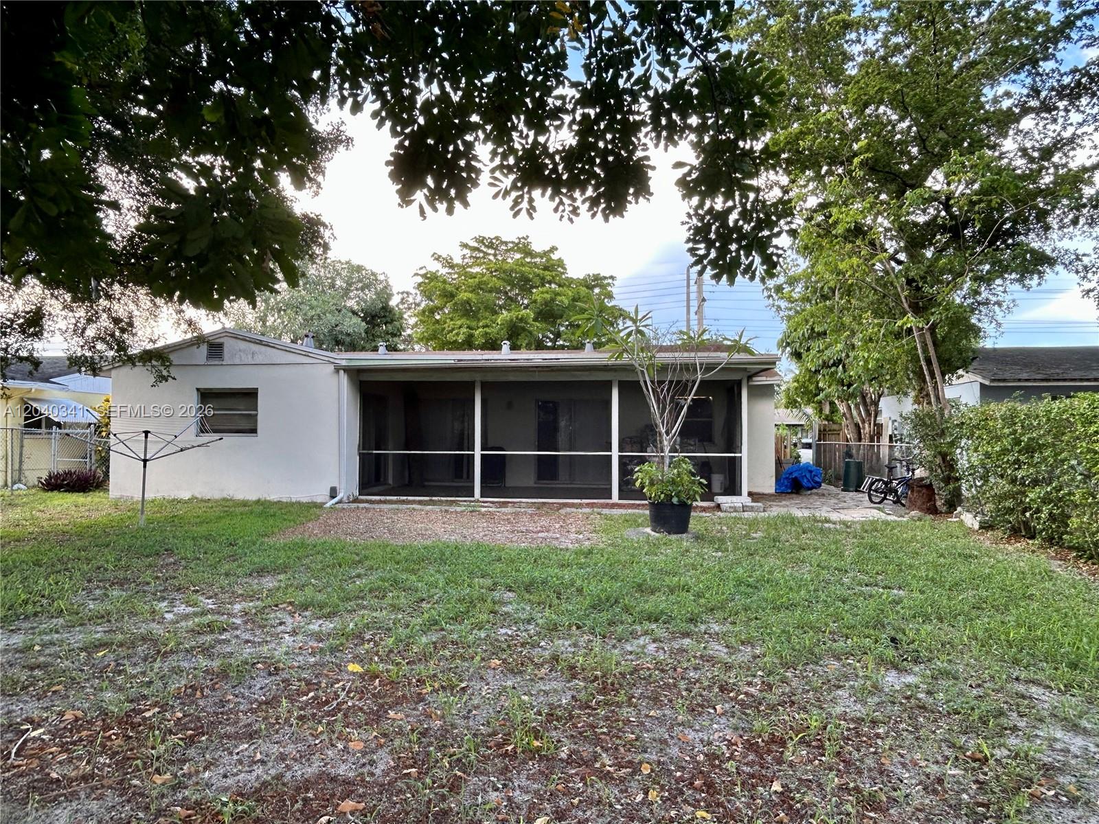 The backyard features a grassy lawn, a screened-in porch, and mature trees — 7262 SW 1st St, Margate FL 33068, MARGATE, FL