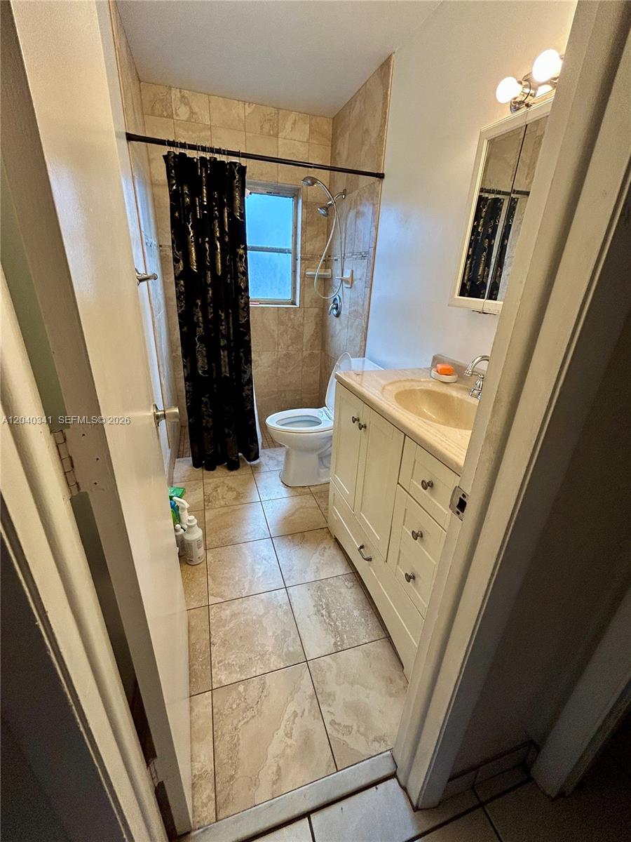 A bathroom features a vanity, a toilet, and a shower area with tiled walls — 7262 SW 1st St, Margate FL 33068, MARGATE, FL